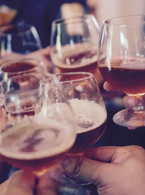 close up og beer glasses being clinked together