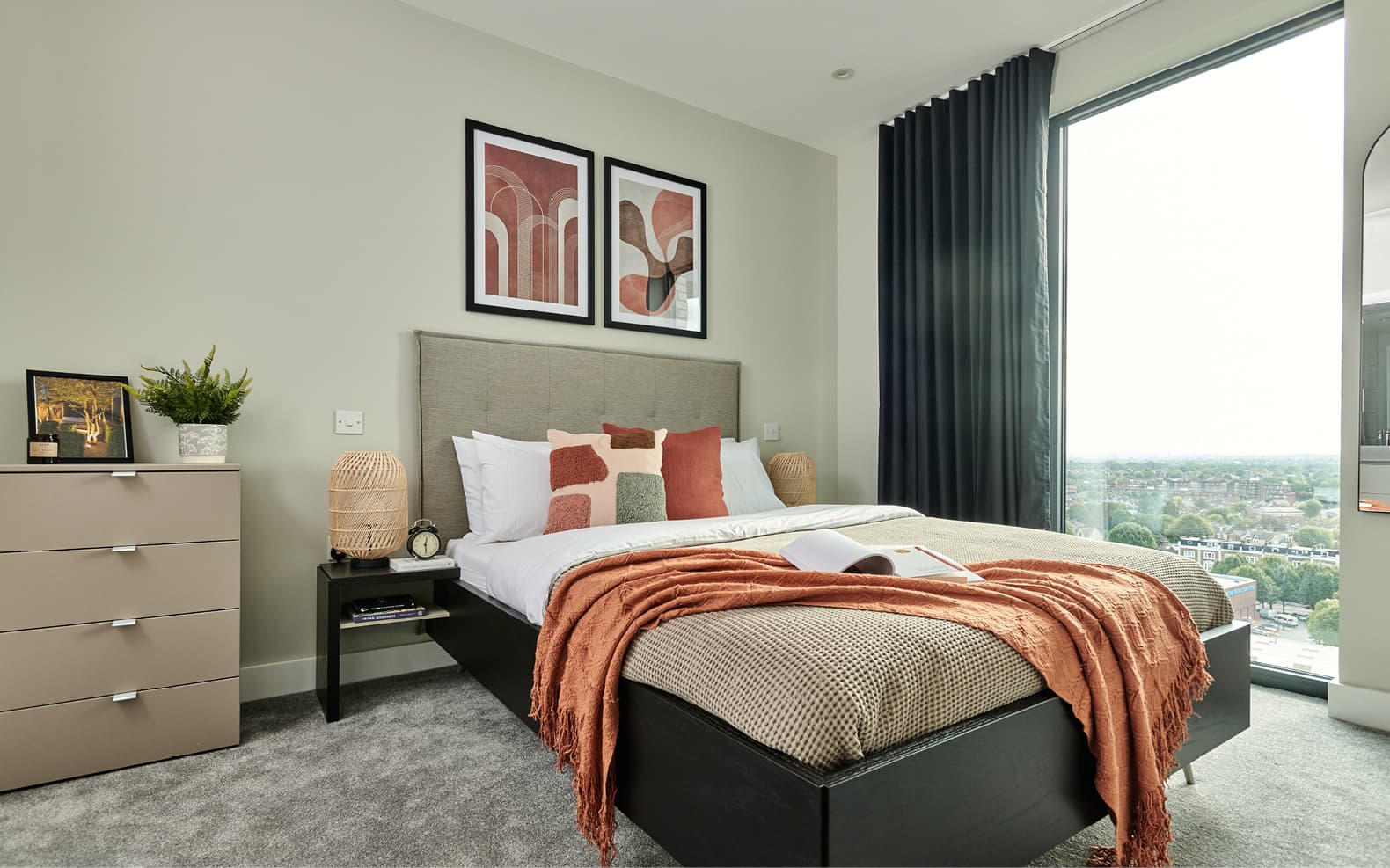 double bed in apartment with bedside table and two artworks on the wall behind the bed